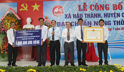 Đồng chí Nguyễn Văn Vĩnh và đồng chí Phạm Anh Tuấn trao Bằng công nhận xã đạt chuẩn NTM và Bảng tượng trưng tặng công trình phúc lợi 1 tỷ đồng cho xã Hậu Thành.
