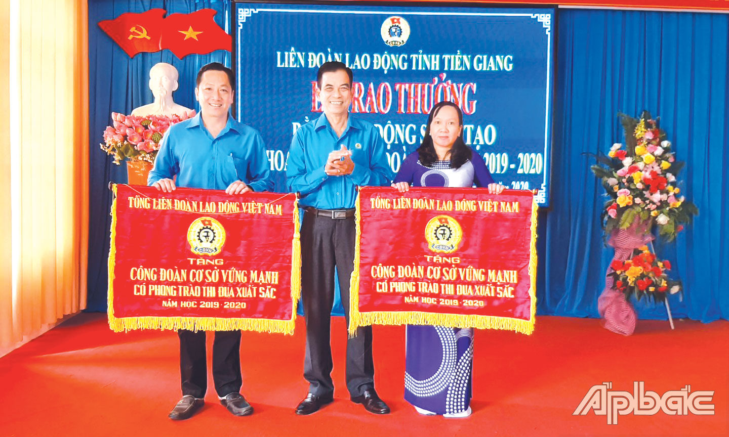 Chủ tịch CĐCS Trường THPT Bình Phục Nhứt Cao Thị Kim Loan (bên phải) nhận Cờ thi đua của Tổng Liên đoàn Lao động Việt Nam. 