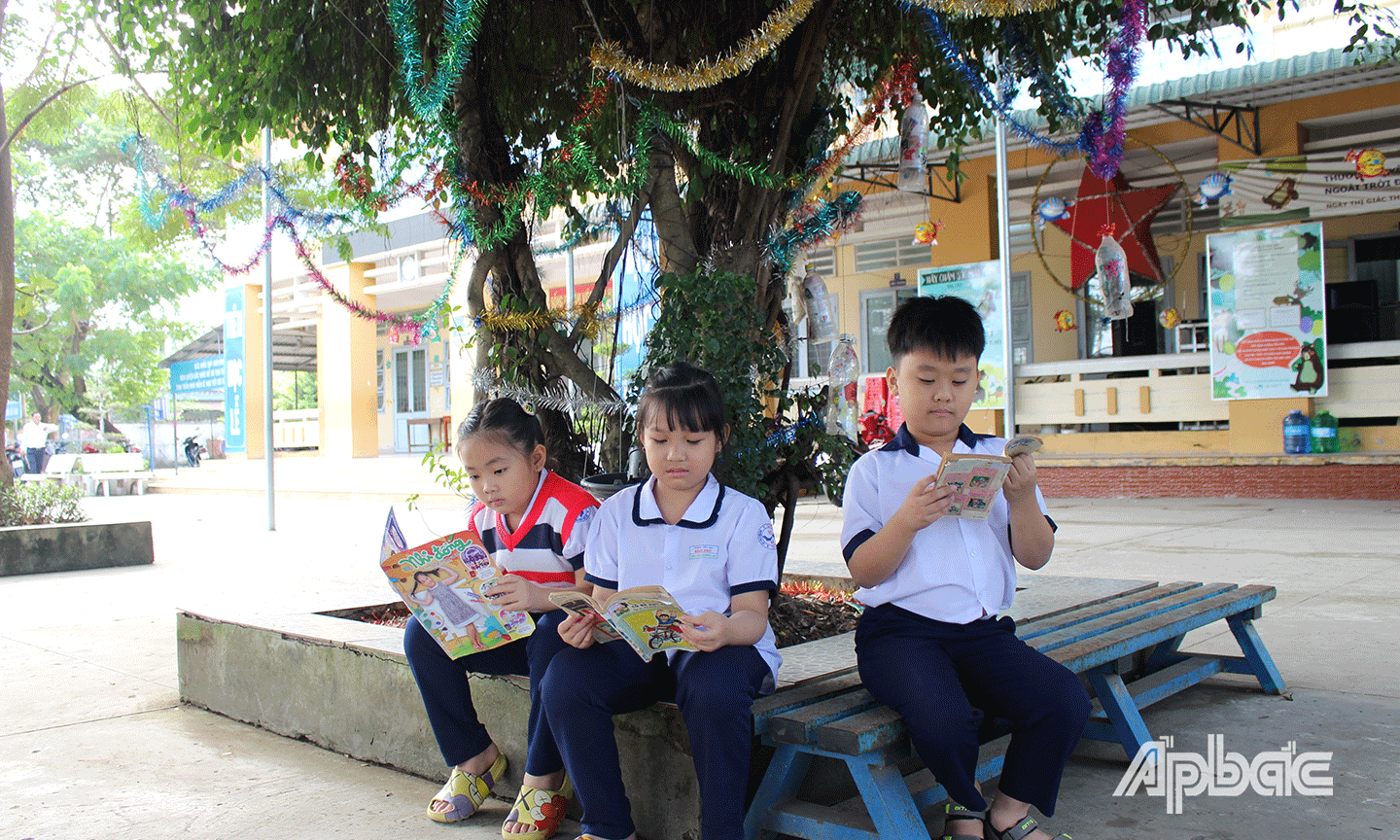 Học sinh chăm chỉ đọc sách dưới không gian mát mẻ của các tán cây xanh. 