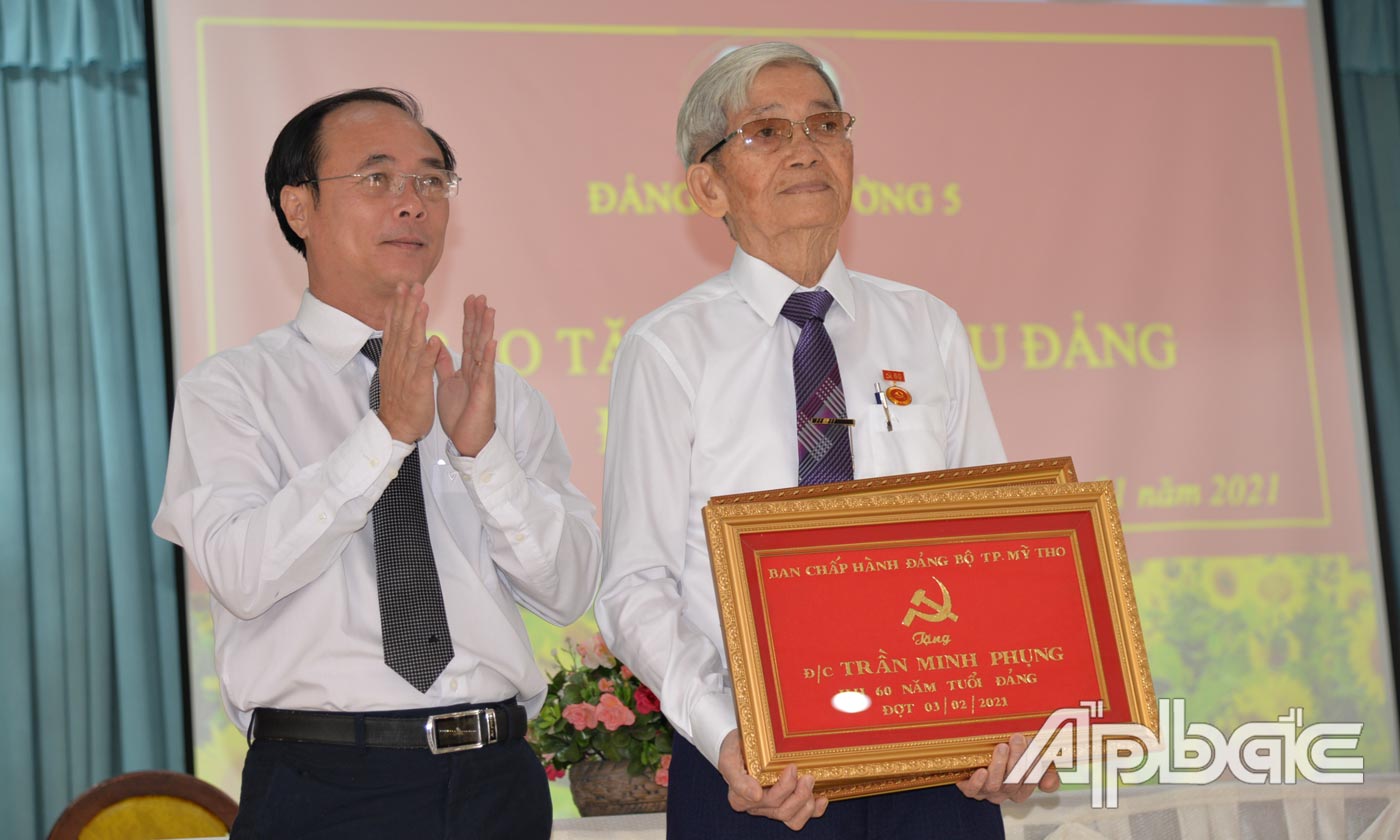 Đồng chí Trần Kim Trát, Ủy viên Ban thường vụ Tỉnh Ủy, Bí thư Thành ủy Mỹ Tho trao huy hiệu 60 năm tuổi Đảng cho đảng viên Trần Minh Phụng.