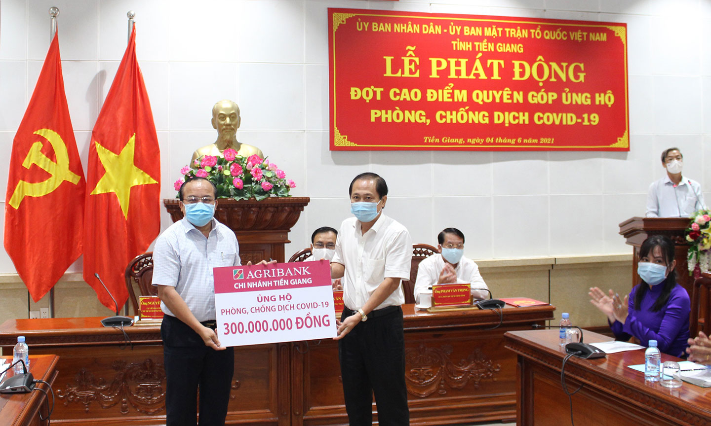 Giám đốc Agribank Tiền Giang Nguyễn Văn Huỳnh (bên phải) trao biển tượng trưng 300 triệu cho Ông Nguyễn Chí Trung, Chủ tịch UBMTTQVN Tỉnh Tiền Giang.