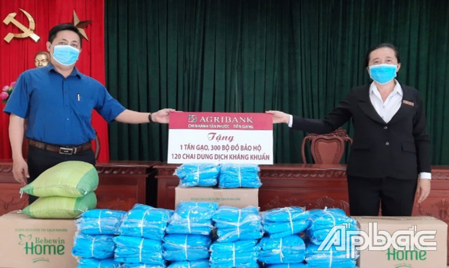 Lãnh đạo Agribank huyện Tân Phước trao  đồ bảo hộ, dung dịch sát khuẩn và Bảng tượng trưng ủng hộ gạo cho các hoàn cảnh khó khăn bị  ảnh hưởng bởi dịch bệnh của huyện Tân Phước. 