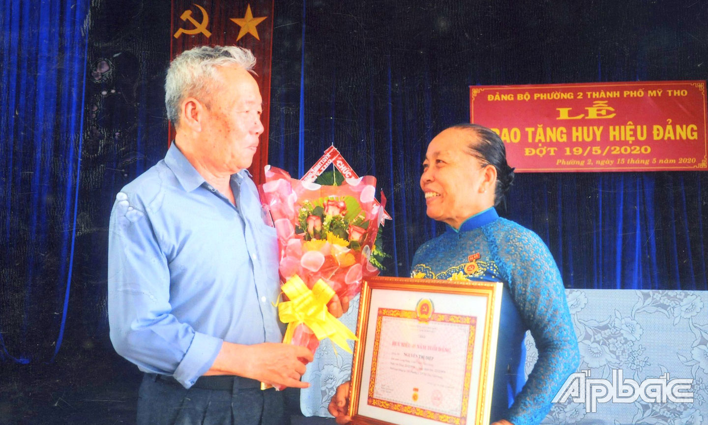  Chú Phú tặng hoa cho cô Diệp nhân dịp cô nhận Huy hiệu 45 năm tuổi Đảng (Ảnh do gia đình cung cấp).