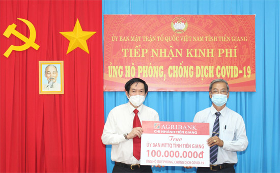 Ông Trương Văn Đoàn (bên trái), Phó Giám đốc Agribank Tiền Giang trao Bảng tượng trưng số tiền 100 triệu đồng ủng hộ phòng, chống dịch Covid-19 cho đồng chí Huỳnh Văn Hải.