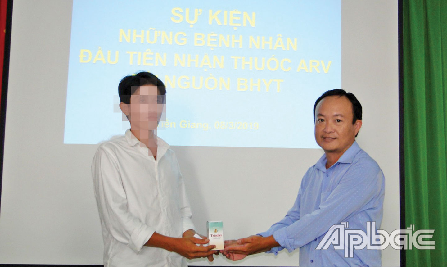 Bác sĩ chuyên khoa 1 Nguyễn Quốc Đạt (bên phải) trao thuốc ARV từ Quỹ Bảo hiểm y tế cho bệnh nhân HIV/AIDS.