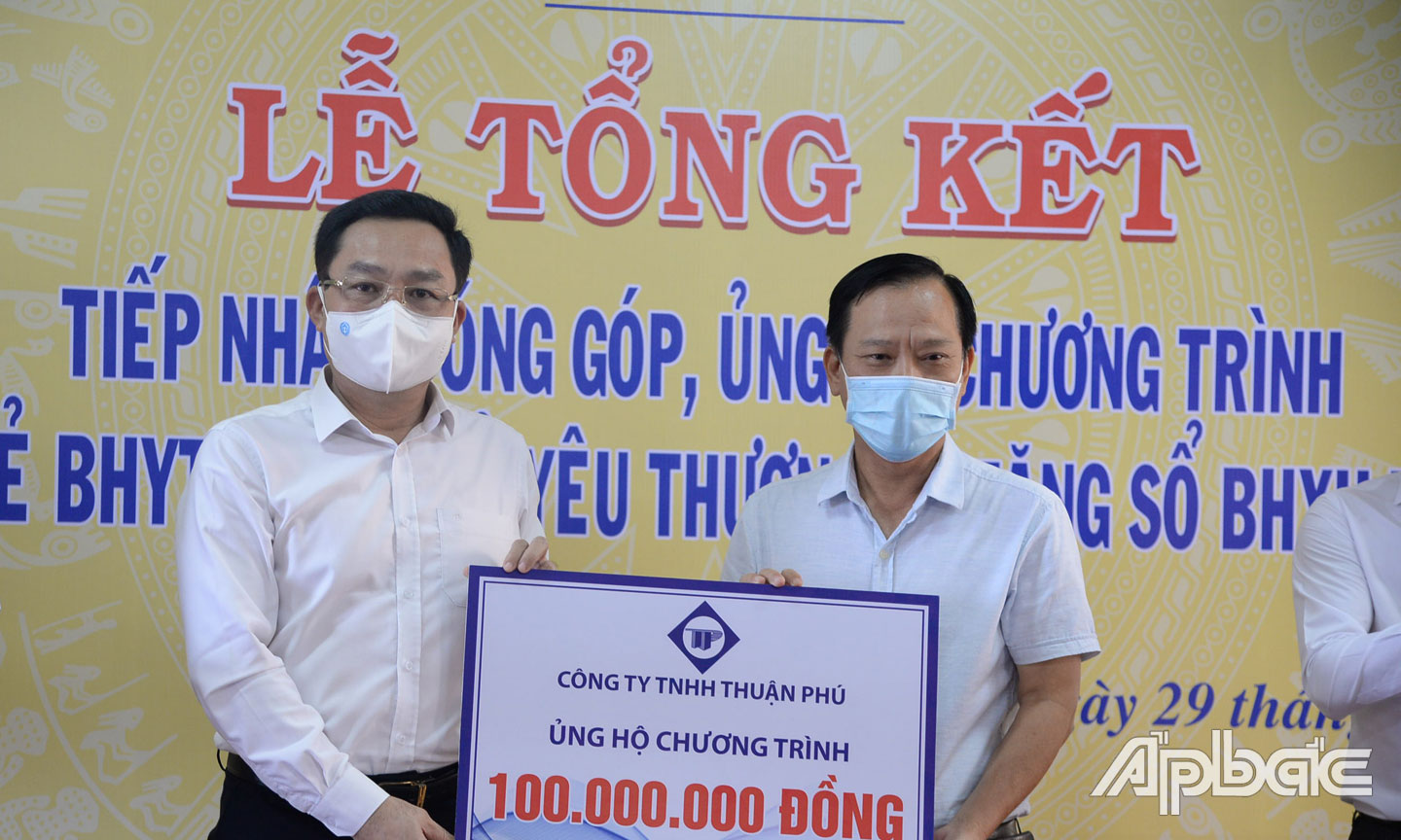 Giám đốc BHXH tỉnh Tiền Giang Võ Khánh Bình (bên phải) nhận Bảng tượng trưng hỗ trợ Chương trình từ các doanh nghiệp.