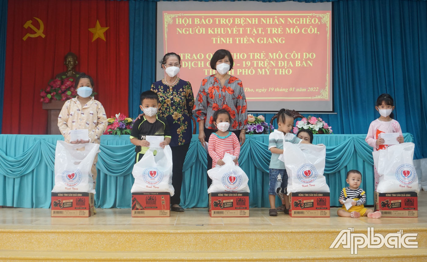 Chủ tịch Hội Bảo trợ bệnh nhân nghèo, người khuyết tật và trẻ mồ côi Võ Thị Chín trao quà cho các em mồ côi có cha (mẹ) chết do dịch bệnh Covid-19 tại TP. Mỹ Tho 
