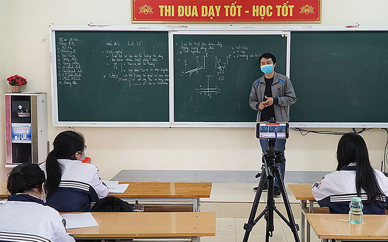 Giáo viên Trường THPT Huỳnh Thúc Kháng (tỉnh Nghệ An) vừa dạy trực tiếp ở lớp vừa phát online cho học sinh đang phải cách ly ở nhà. (Ảnh: MỸ HÀ) 