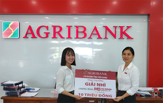 Phó Giám đốc Agribank huyện Gò Công Đông Phùng Thị Lệ Hằng trao biển tượng trưng số tiền trúng thưởng giải Nhì cho khách hàng Nguyễn Thị Mai Thi (bên trái)