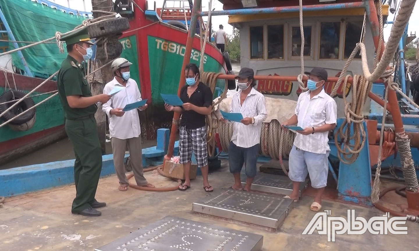 Cán bộ Đội Vận động quần chúng Đồn BP Kiểng Phước, BĐBP Tiền Giang tuyên truyền và phát tờ rơi cho ngư dân trước khi ra khơi. (