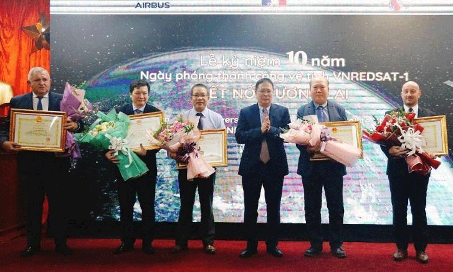 VAST President Chau Van Minh presents flowers and certificates of merits to contributors to the VNREDSat-1 project.