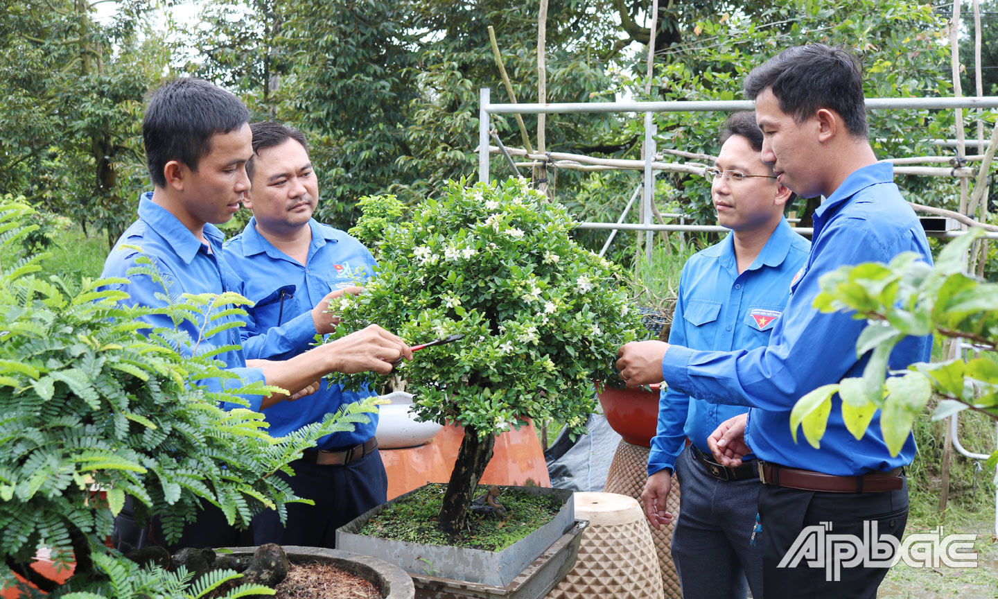 Anh Trãi  (bìa trái) chia sẻ kỹ thuật trồng bonsai cho  thanh niên địa phương. 