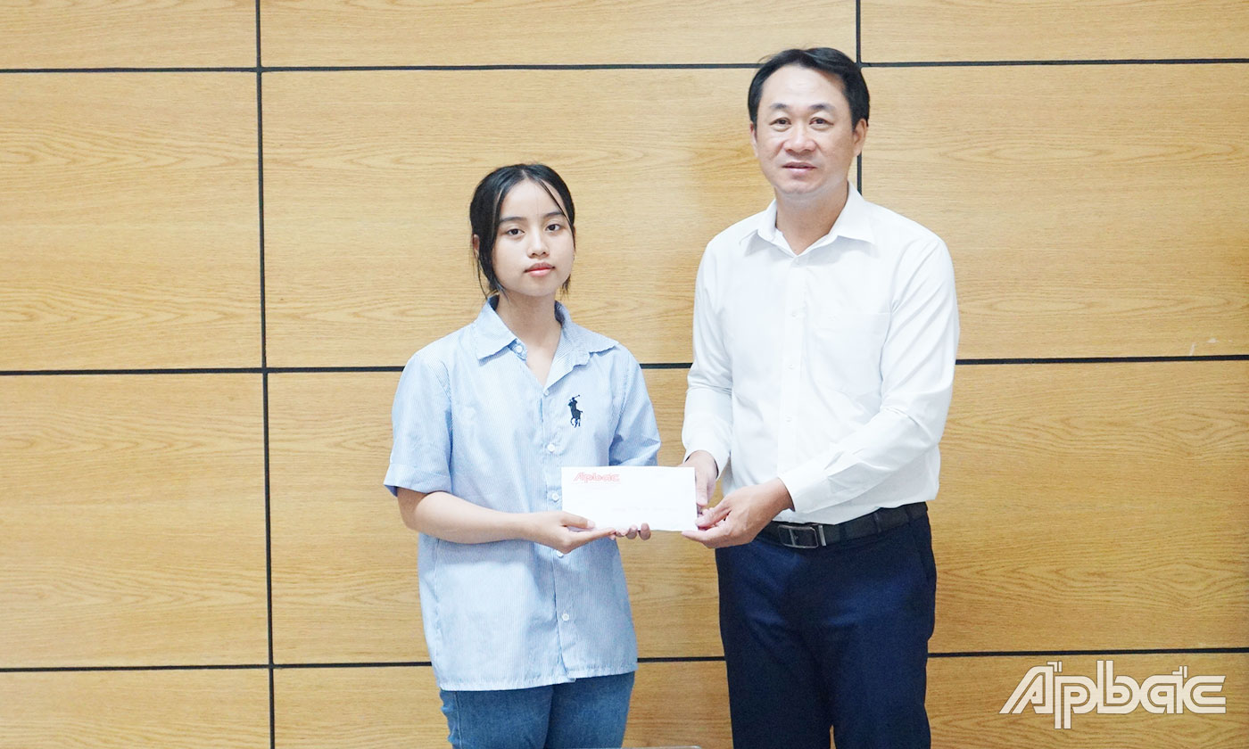 Phó Giám đốc Công ty TNHH MTV Xổ số kiến thiết Tiền Giang Trần Văn Giang trao học bổng cho em Trần Thị Hồng Ngọc.