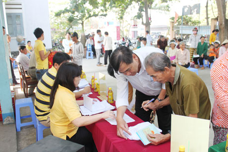 Ông Nguyễn Minh Tân, Phó Tổng Biền tập Báo Ấp Bắc hướng dẫn bà con làm thủ tục nhận quà.