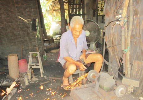 Ông Ba Thợ rèn đang mài dao, tia lửa bung ra như pháo hoa.