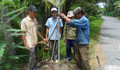 Cán bộ và nhân dân ấp Long Thới đang trồng trụ đèn.