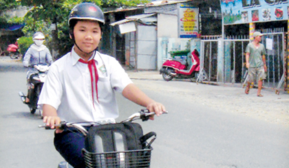 Đi xe đạp điện đội nón bảo hiểm để  đảm bảo an toàn. Ảnh: Ngọc Trung	