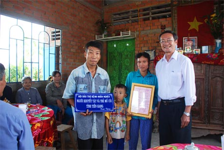 Ông Phan Văn Hà, Chủ tịch Hội Bảo trợ bệnh nhân nghèo, người tàn tật và trẻ mồ côi tỉnh trao quyết định tặng nhà cho gia đình cháu Quí.