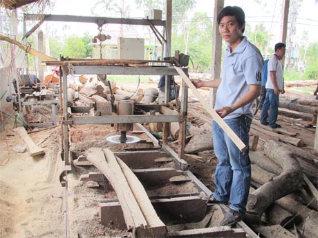 Anh Phạm Hồng Thơm bên cạnh máy cưa dĩa do anh sáng chế.