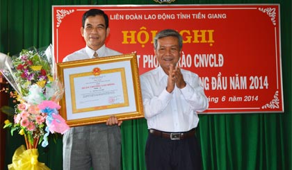 Ông Trần Long Thôn, Trưởng Ban Dân vận Tỉnh ủy thừa ủy quyền của Chủ tịch nước trao Huân chương Lao động hạng Nhì cho ông Trương Văn Hiền.