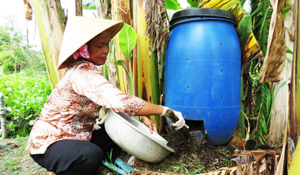 2. Chị Trang lấy phân hữu cơ từ thùng ủ rác compost.