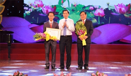 Nhan Dan Newspaper Editor-in-Chief Thuan Huu (middle) presents awards to the first prize-winner, Nguyen Bao Tri (first from left), and the Secretary of An Phu district’s Party Committee, Nguyen Van Thanh