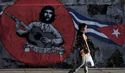 Một phụ nữ đi bức graffiti của Che Guevara và lá cờ Cuba trên đường phố thủ đô La Habana. Nguồn: Reuters