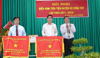 Lãnh đạo xã Vĩnh Hựu (bên trái) nhận Cờ thi đua của UBND tỉnh năm 2014.