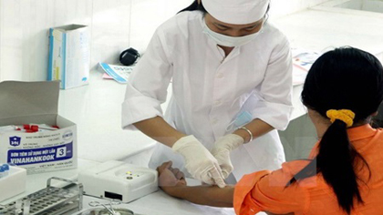 A health worker at Ninh Binh Province's HIV/AIDS Prevention and Control Centre takes blood samples from a woman. 