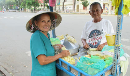 Vợ chồng ông Định chặt mía chuẩn bị bán cho các em học sinh giờ ra chơi.