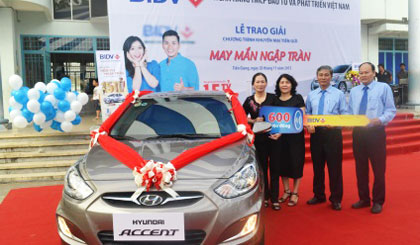 Lãnh đạo BIDV chi nhánh Tiền Giang trao xe cho bà Trần Thị Tím.