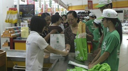 Supermarket staff give eco-friendly bags to customers at a FiviMart. (Source: VNA)