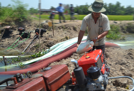 Ông Dương Văn Việt túc trực bên máy bơm nước để tranh thủ  lấy nước cho những trà lúa đang trổ bông.
