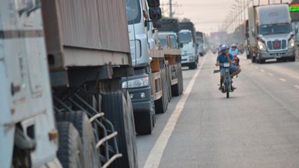 Hàng trăm xe tải và cotainer đậu 2 bên tuyến đường khiến xe qua khu vực trên phải di chuyển sang làn xe 4 bánh.
