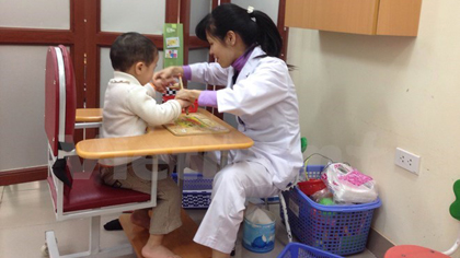 A medical worker from the National Hospital of Pediatrics tends to a child with autism (Photo: VNA)