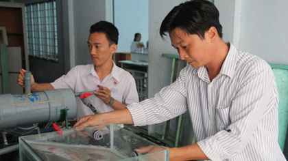 Truong Huu Dung (R) and a student on his team at Nguyen Dinh Chieu High School in Ben Tre City, Ben Tre Province, are pictured monitoring the water desalination machine.