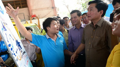 Dinh La Thang (R), Secretary of the Ho Chi Minh City Party Committee and member of the Politburo, listens to a young entrepreneur presenting his start-up project at the ceremony to launch a program to encourage young people's entrepreneurship on March 27, 2016.