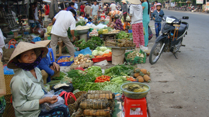 A consumer buys vegetables on street (Source: VNA)