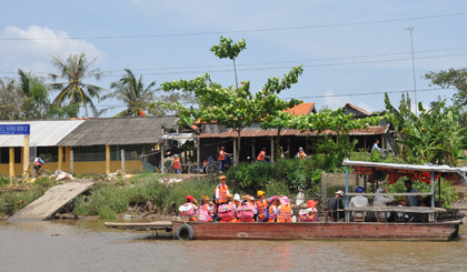 Các em học sinh mặc áo phao đi đò ngang kinh Chợ Gạo.