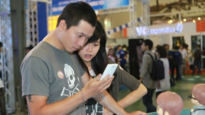 Customers use smartphones at an exhibition in Ha Noi. Smartphone subscriptions in Viet Nam are expected to triple from around 30 million in 2015 (Photo:VNA)