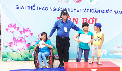 VĐV Đỗ Thị Khuyên (bên trái) nhận Huy chương Bạc môn bơi lội tại giải thể thao người khuyết tật toàn quốc, diễn ra vào tháng 7 vừa qua tại TP. Hồ Chí Minh.