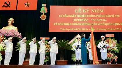 Vice President Dang Thi Ngoc Thinh pins the second-class Fatherland Defence Order to the traditional flag of Protection Division 180 at the ceremony. (Credit: sggp.org.vn) 