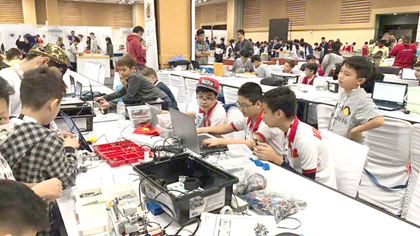 Three Vietnamese students are programming the robots for the competition in WRO (PHoto: SGGP)