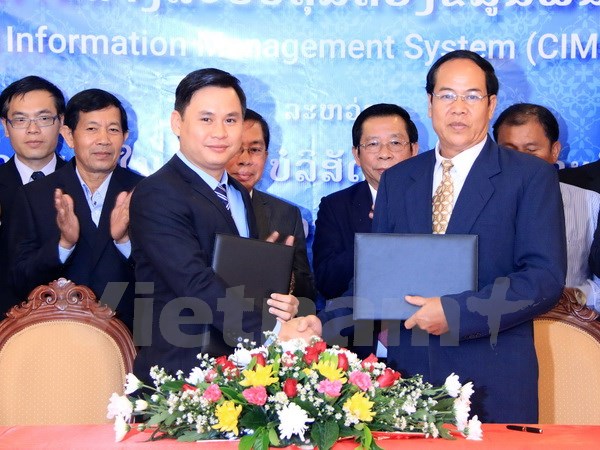 Ông Cao Anh Sơn (trái), Tổng Giám đốc Công ty Star Telecom và ông Thongchan Sivilay, Cục trưởng Cục quản lý hộ khẩu, Bộ Nội vụ Lào đang trao cho nhau Hợp đồng. (Ảnh: Phạm Kiên/Vietnam+)