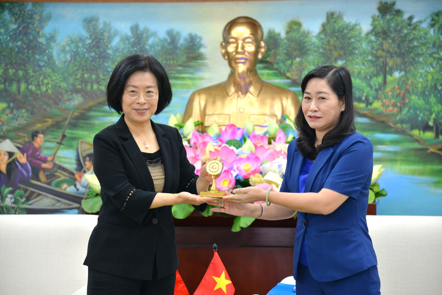 Đồng chí Châu Thị Mỹ Phương, Trưởng Ban Tuyên giáo Tỉnh ủy Giang trao logo biểu tượng của tỉnh đến bà Ôn Hồng Ngạn