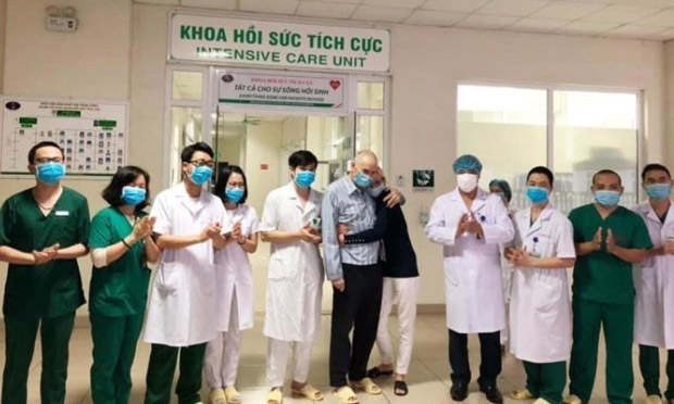 Vợ chồng bệnh nhân người Anh (mặc áo bệnh nhân/áo đen) và các nhân viên y tế Bệnh viện Bệnh nhiệt đới Trung ương. (Ảnh: PV/Vietnam+)