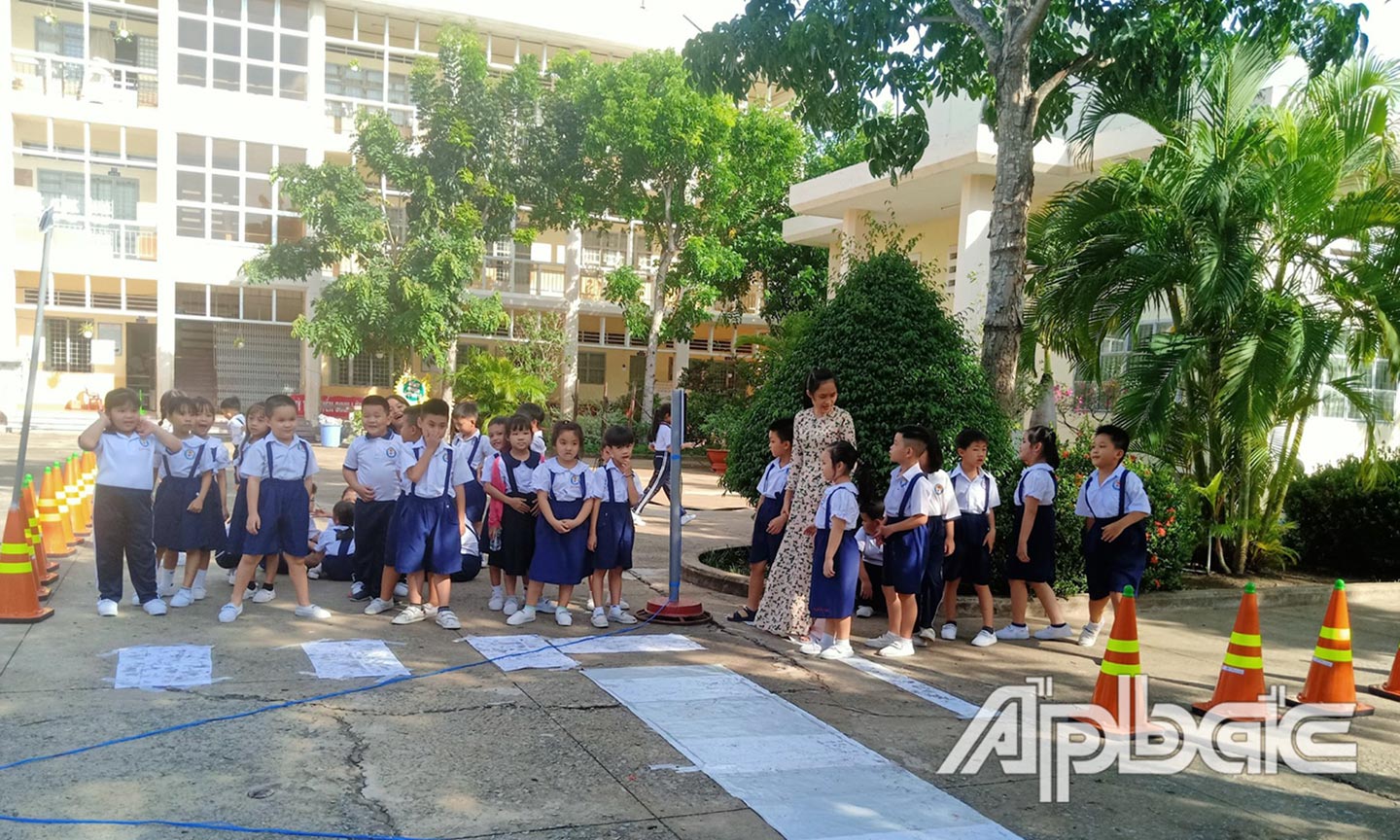 Giáo viên Trường Tiểu học Nguyễn Huệ hướng dẫn học sinh cách tham gia giao thông đúng quy định. 