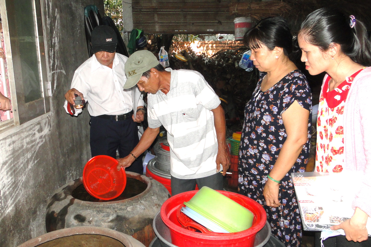 Cán bộ y tế hướng dẫn hộ dân thả cá 7 màu diệt lăng quăng trong dụng cụ chứa nước