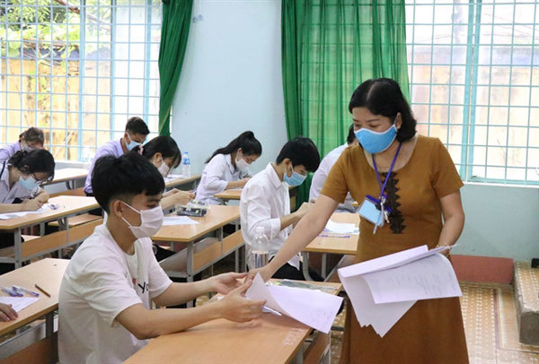 An exam supervisor gives questions to students who sit for the second phase of the national high school graduation exam at Chu Van An High School in the Central Highland city of Buon Ma Thuot, in Dak Lak Province.  