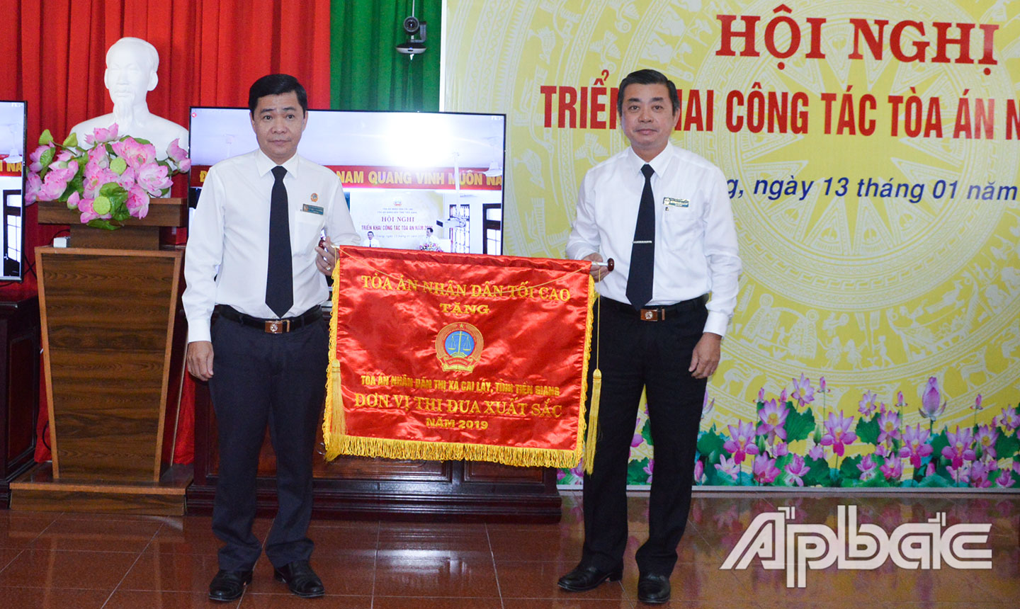 Chánh án TAND tỉnh Huỳnh Xuân Long (bìa phải) trao “Cờ thi đua TAND” của TAND Tối cao cho Chánh án TAND TX. Cai Lậy Mai Văn Hùng Cường.